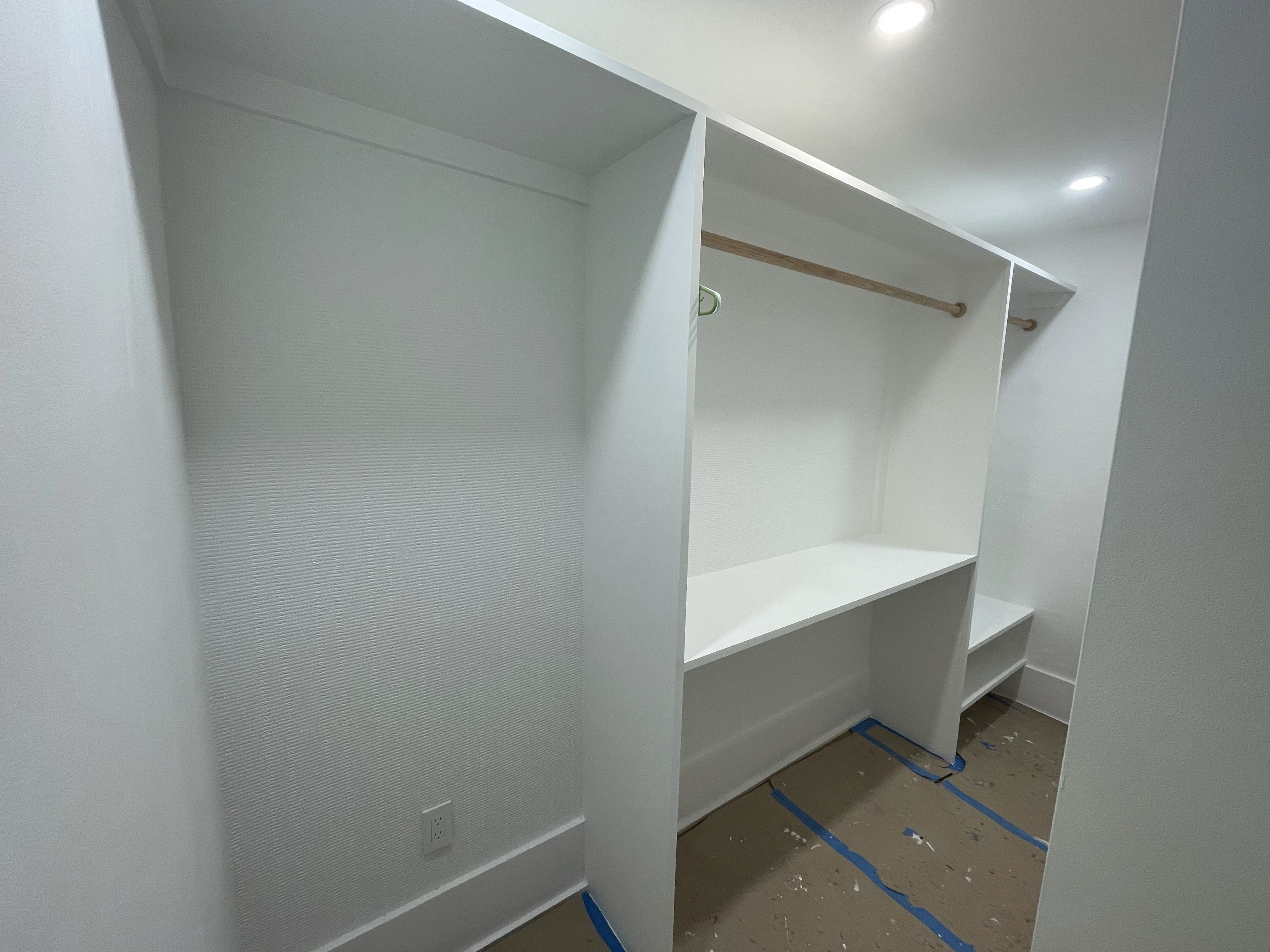 Custom walk-in closet with white built-in shelving and hanging rod