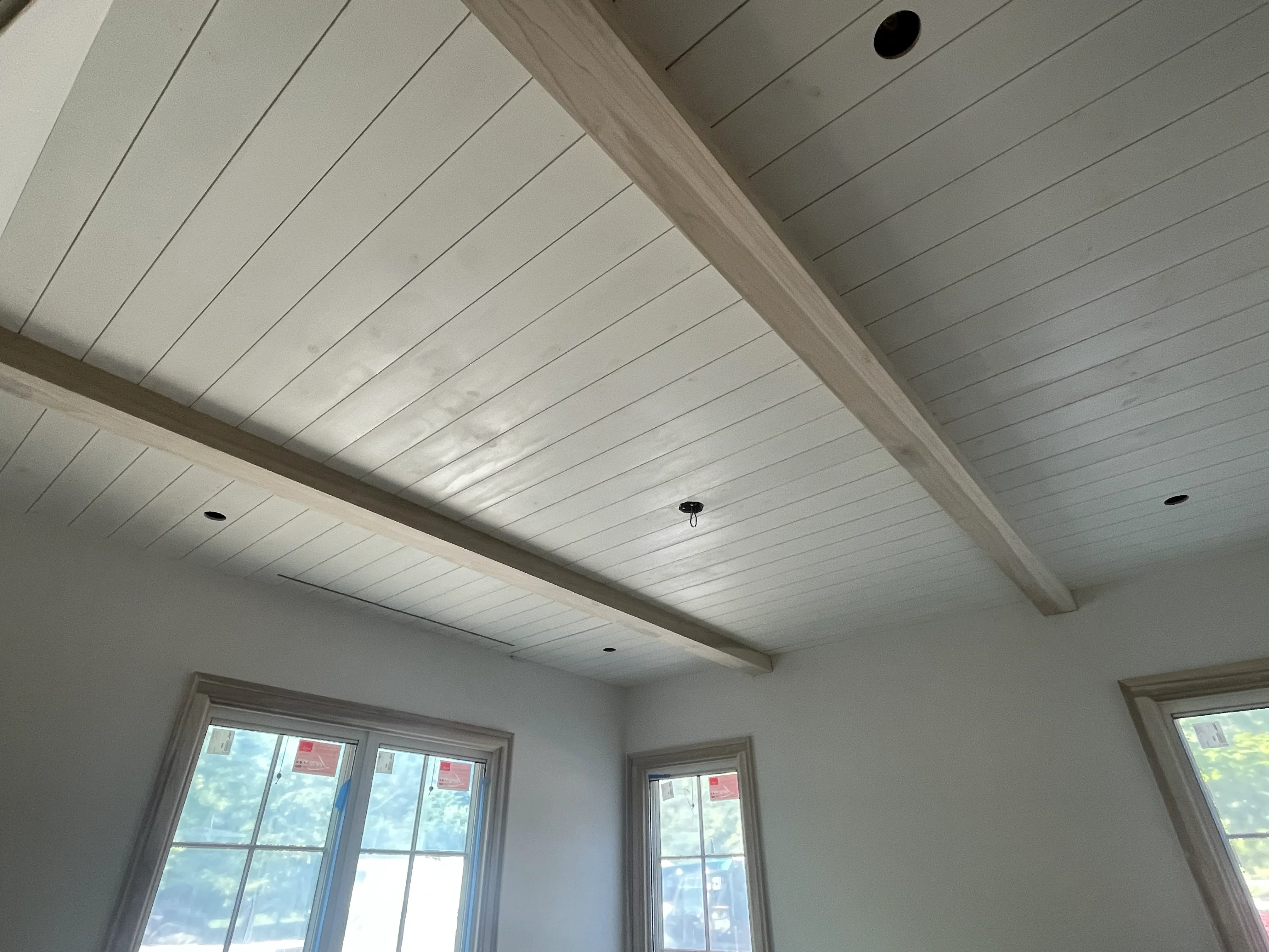 Shiplap ceiling with exposed beams and large windows