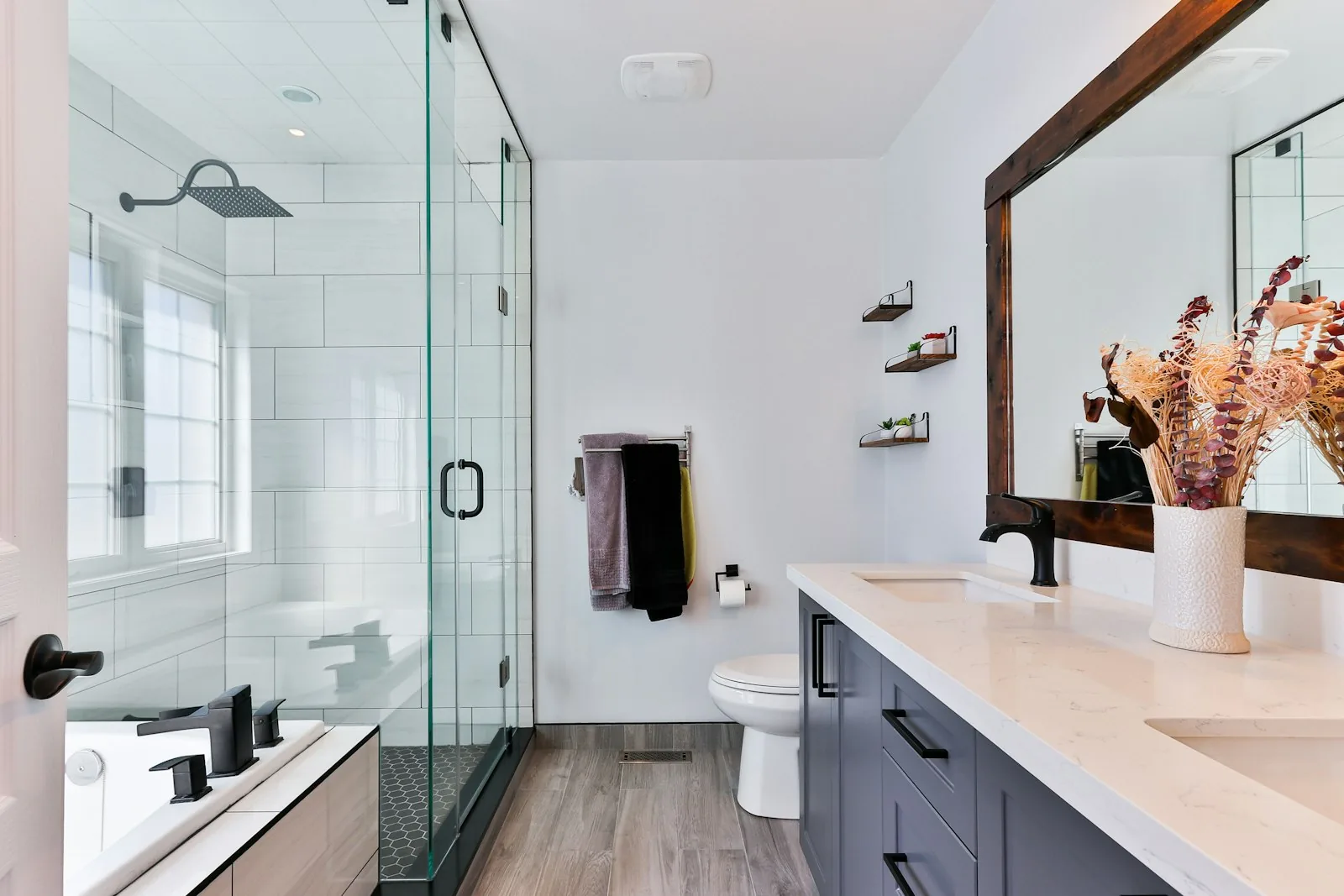 Modern bathroom remodel with glass shower, vanity, and wood-framed mirror — by Gerhard and Sons in Northwest Michigan